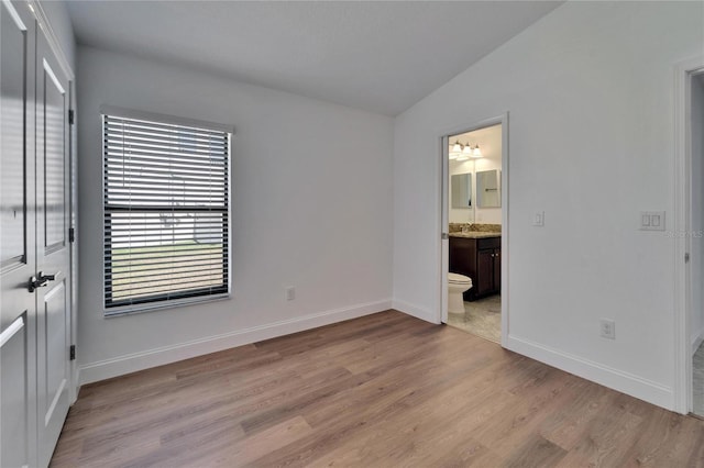 12055 Cardinal Flower Dr, Riverview, FL 33579 - unfurnished bedroom featuring vaulted ceiling, wood finished floors, baseboards, ensuite bathroom, and a sink
