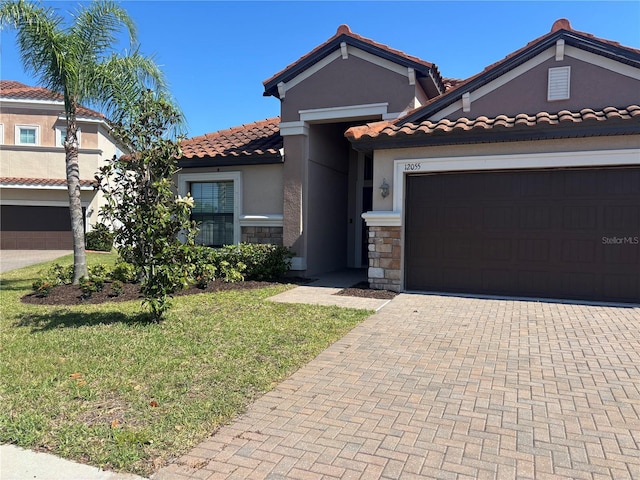 12055 Cardinal Flower Dr, Riverview, FL 33579 - mediterranean / spanish home with a tile roof, a front yard, stone siding, decorative driveway, and stucco siding
