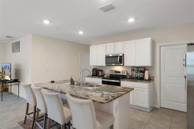 2449 Moon Shadow Rd, New Port Richey, FL 34655 - kitchen with appliances with stainless steel finishes, a sink, an island with sink, light tile patterned floors, and white cabinetry