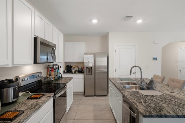 2449 Moon Shadow Rd, New Port Richey, FL 34655 - kitchen with appliances with stainless steel finishes, arched walkways, white cabinets, a center island with sink, and recessed lighting