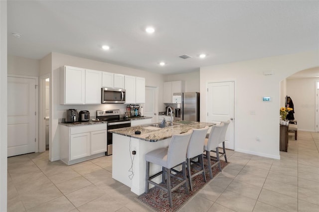 2449 Moon Shadow Rd, New Port Richey, FL 34655 - kitchen with appliances with stainless steel finishes, a sink, arched walkways, a breakfast bar area, and a center island with sink