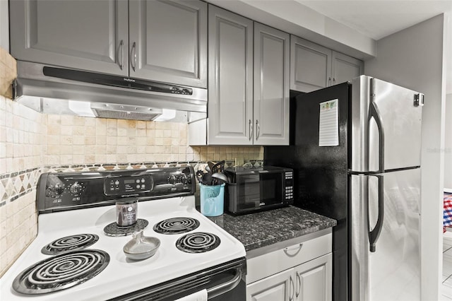 kitchen featuring range with electric stovetop, under cabinet range hood, freestanding refrigerator, black microwave, and tasteful backsplash
