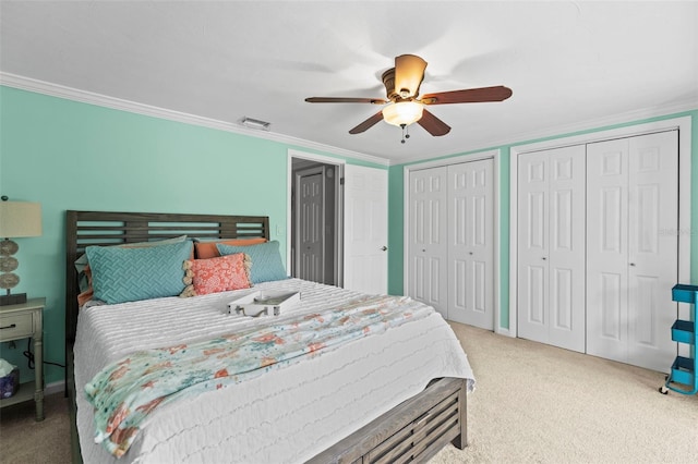 carpeted bedroom with two closets, crown molding, and a ceiling fan