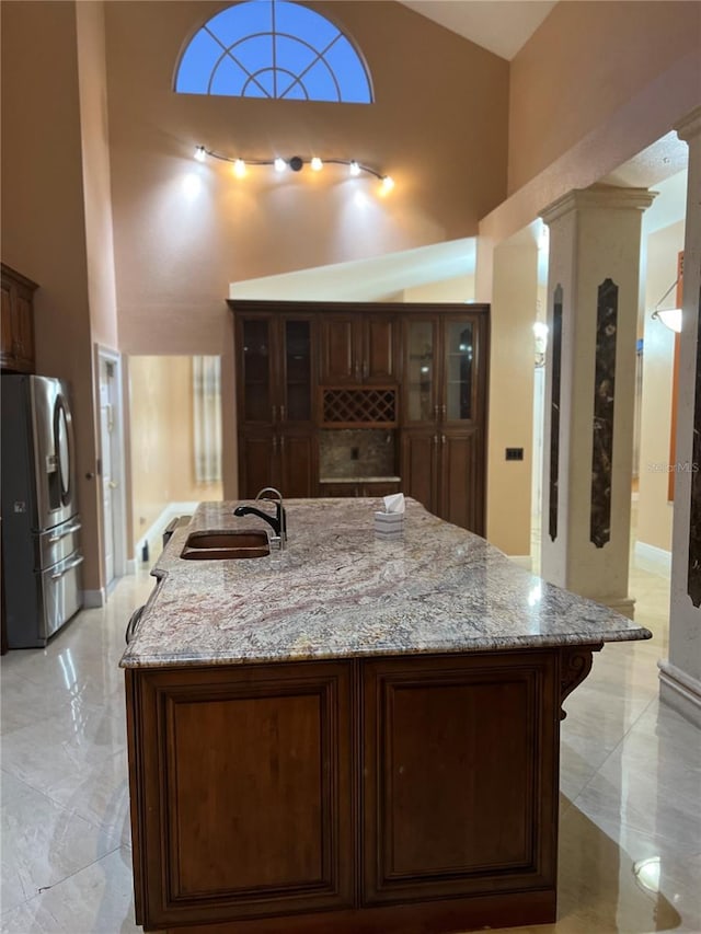 18104 Sweet Jasmine Dr, Tampa, FL 33647 - kitchen with stainless steel fridge with ice dispenser, a spacious island, high vaulted ceiling, light stone counters, and glass insert cabinets