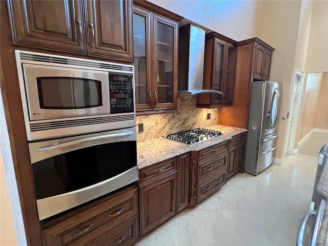 18104 Sweet Jasmine Dr, Tampa, FL 33647 - kitchen featuring appliances with stainless steel finishes, wall chimney range hood, backsplash, dark brown cabinets, and light stone counters