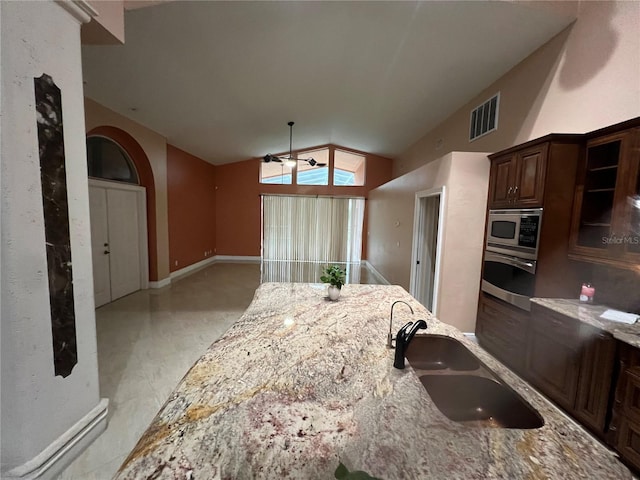 18104 Sweet Jasmine Dr, Tampa, FL 33647 - kitchen with stainless steel appliances, vaulted ceiling, light stone countertops, a ceiling fan, and dark brown cabinetry