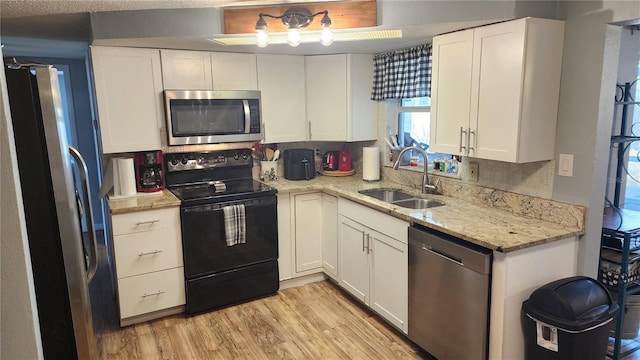 kitchen featuring appliances with stainless steel finishes, a sink, and white cabinetry