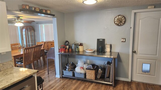 bar area featuring dark wood finished floors, a ceiling fan, and a textured ceiling