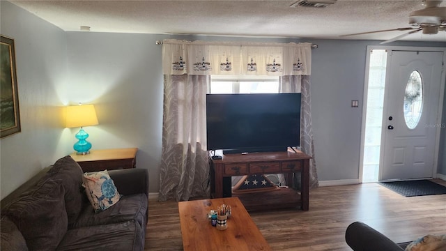 living room featuring ceiling fan, wood finished floors, a textured ceiling, and baseboards