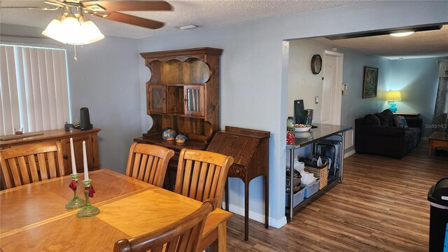 dining area featuring wood finished floors, a ceiling fan, and a textured ceiling