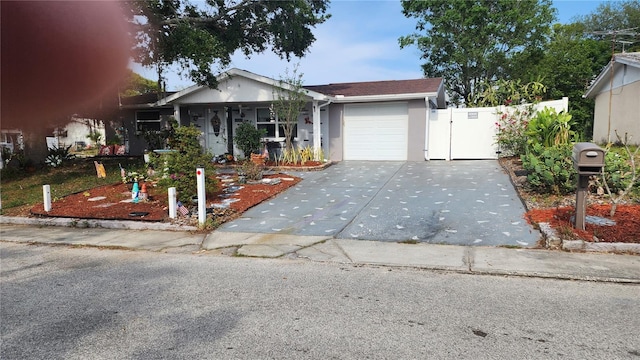 view of front of house featuring concrete driveway, a garage, stucco siding, fence, and a gate