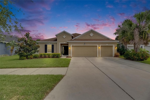 view of front of house featuring stucco siding, an attached garage, driveway, and a front yard