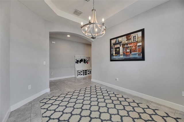 unfurnished room featuring arched walkways, tile patterned flooring, a chandelier, and baseboards