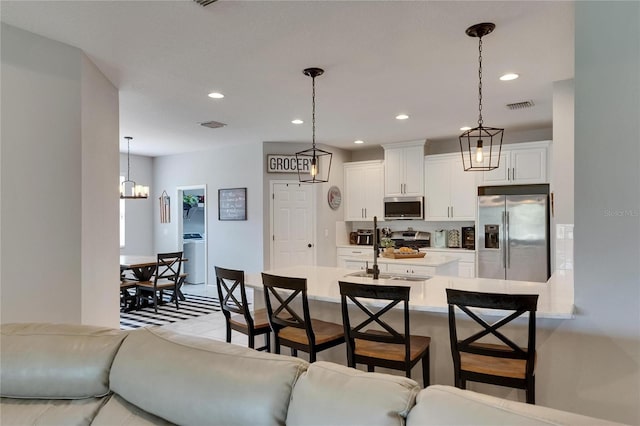 kitchen with stainless steel appliances, a sink, light countertops, a breakfast bar area, and white cabinetry