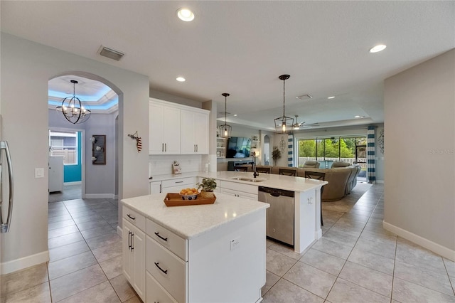 kitchen featuring dishwasher, a raised ceiling, open floor plan, a kitchen island, and a sink