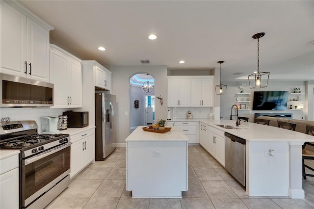kitchen featuring appliances with stainless steel finishes, a sink, open floor plan, a peninsula, and tasteful backsplash