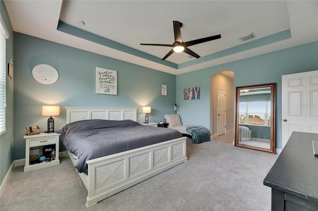 bedroom featuring a raised ceiling, carpet flooring, and arched walkways
