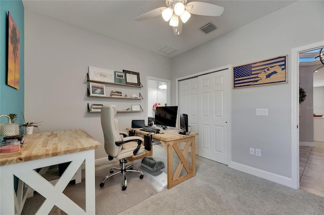 home office with a ceiling fan, baseboards, and light colored carpet