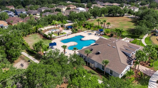 aerial view of residential area with a pool and a tree filled landscape