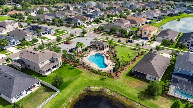 aerial perspective of suburban area featuring a pool area and a large body of water