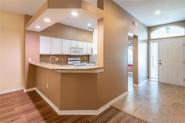 19025 Callaway Ct, Tampa, FL 33647 - kitchen featuring white appliances, light stone countertops, white cabinets, baseboards, and a peninsula