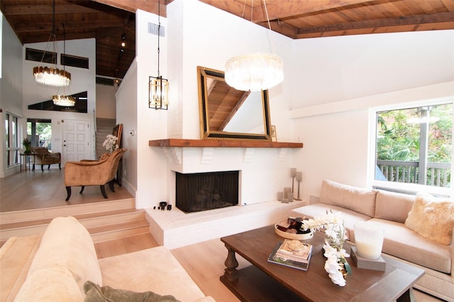 living room featuring wooden ceiling, beam ceiling, wood finished floors, a brick fireplace, and high vaulted ceiling