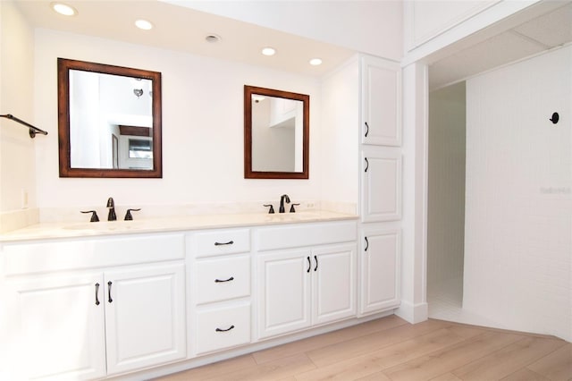 bathroom with wood finished floors, recessed lighting, a tile shower, and double vanity