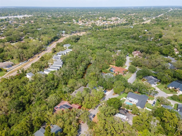 aerial view of property and surrounding area with a heavily wooded area and nearby suburban area