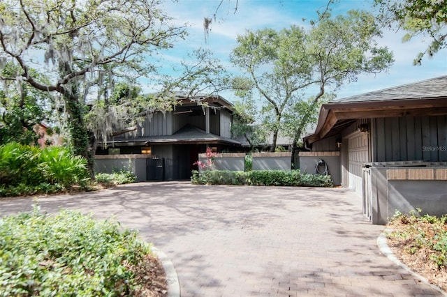 1296 Weybridge Ln, Dunedin, FL 34698 - view of side of home with decorative driveway, a garage, and board and batten siding