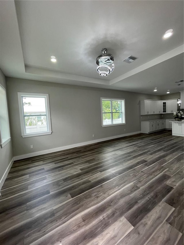 12308 Pittsfield Ave, Tampa, FL 33624 - unfurnished living room featuring a tray ceiling, baseboards, dark wood-style floors, and recessed lighting