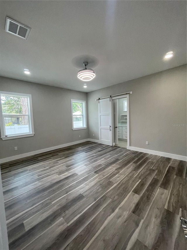 12308 Pittsfield Ave, Tampa, FL 33624 - unfurnished bedroom with a barn door, dark wood finished floors, baseboards, connected bathroom, and recessed lighting