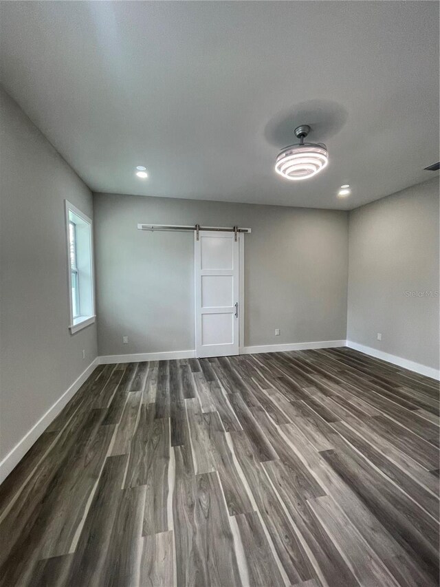 12308 Pittsfield Ave, Tampa, FL 33624 - empty room with baseboards, dark wood-type flooring, a barn door, and recessed lighting