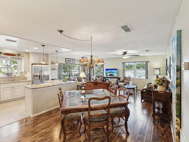 5980 Terrace Park Dr N Unit 214, Saint Petersburg, FL 33709 - dining area featuring a ceiling fan, light wood-type flooring, a textured ceiling, and a chandelier