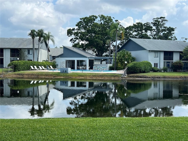 back of property with a water view and a lawn