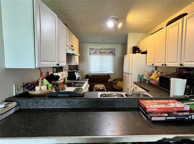 kitchen with under cabinet range hood, white appliances, dark countertops, white cabinets, and a textured ceiling