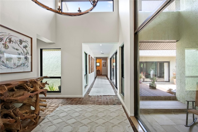 4009 Carrollwood Village Dr, Tampa, FL 33618 - hallway featuring baseboards, brick flooring, a chandelier, and a high ceiling