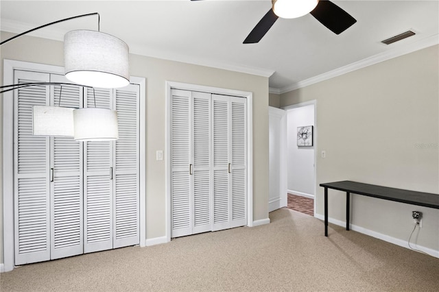 4009 Carrollwood Village Dr, Tampa, FL 33618 - unfurnished bedroom featuring crown molding, carpet floors, two closets, baseboards, and ceiling fan