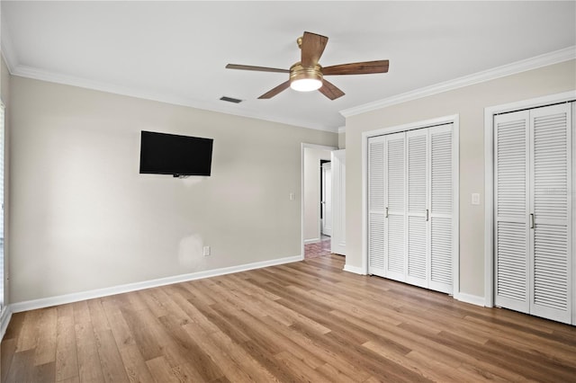 4009 Carrollwood Village Dr, Tampa, FL 33618 - unfurnished bedroom with two closets, ornamental molding, wood finished floors, baseboards, and a ceiling fan