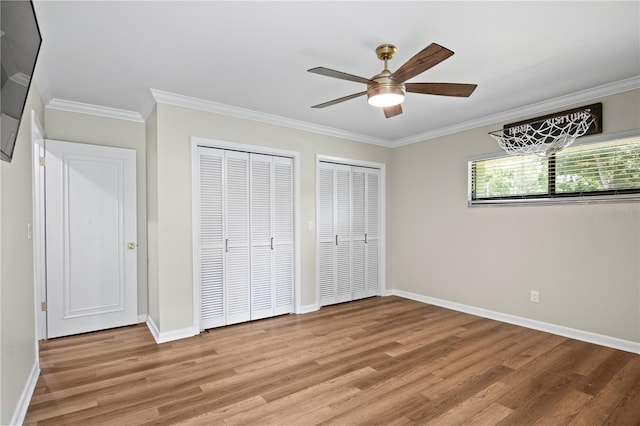 4009 Carrollwood Village Dr, Tampa, FL 33618 - unfurnished bedroom featuring multiple closets, light wood-style floors, ornamental molding, baseboards, and a ceiling fan