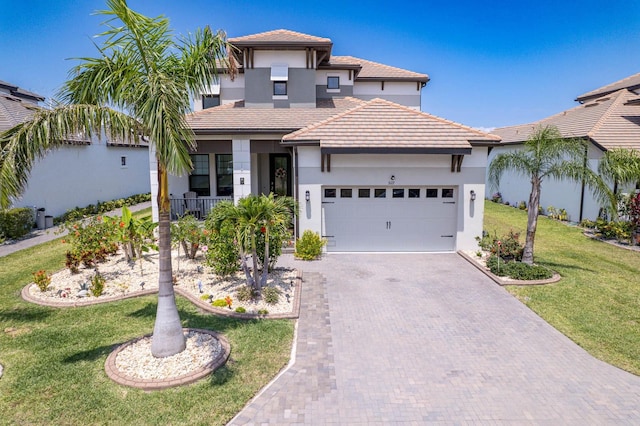 mediterranean / spanish house with an attached garage, stucco siding, decorative driveway, a front yard, and a tiled roof