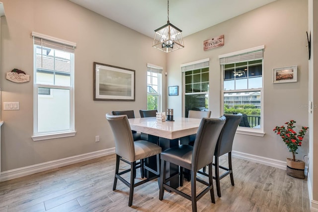 dining space featuring a chandelier, light wood-style flooring, and baseboards