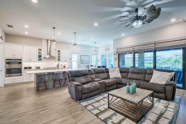 living area featuring light wood-style flooring, a ceiling fan, and recessed lighting