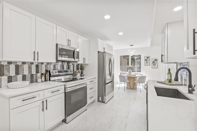 13934 Clubhouse Cir Unit 8, Tampa, FL 33618 - kitchen with appliances with stainless steel finishes, a sink, white cabinetry, tasteful backsplash, and light marble finish floors