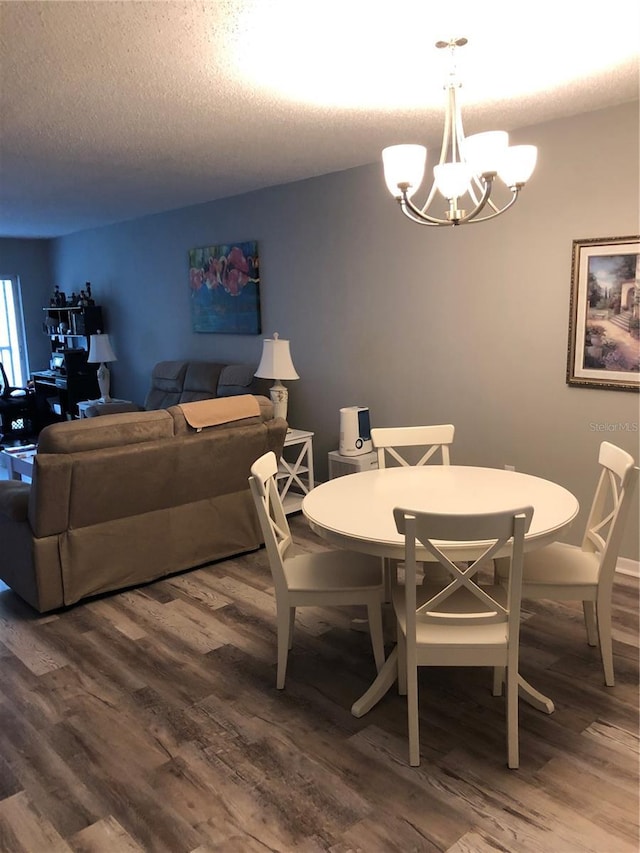 860 Virginia St Unit 308, Dunedin, FL 34698 - dining area featuring a chandelier, dark wood finished floors, and a textured ceiling