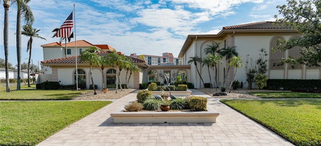 rear view of property with a tiled roof, stucco siding, and a lawn