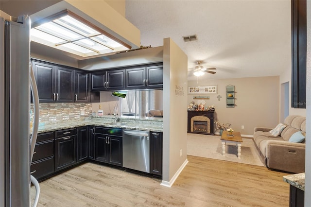 2816 Manor Hill Dr, Brandon, FL 33511 - kitchen with stainless steel appliances, open floor plan, light wood-type flooring, dark cabinetry, and backsplash