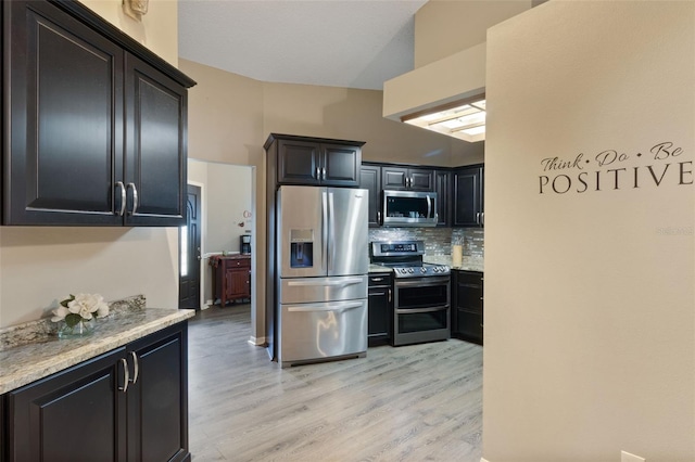 2816 Manor Hill Dr, Brandon, FL 33511 - kitchen with appliances with stainless steel finishes, backsplash, light wood-style flooring, light stone countertops, and vaulted ceiling