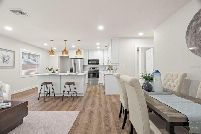 dining room featuring light wood-style flooring, recessed lighting, and baseboards