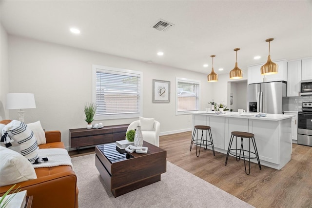 living area with light wood-style flooring, recessed lighting, and baseboards