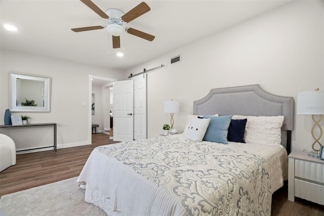 bedroom featuring wood finished floors, a barn door, recessed lighting, baseboards, and ceiling fan